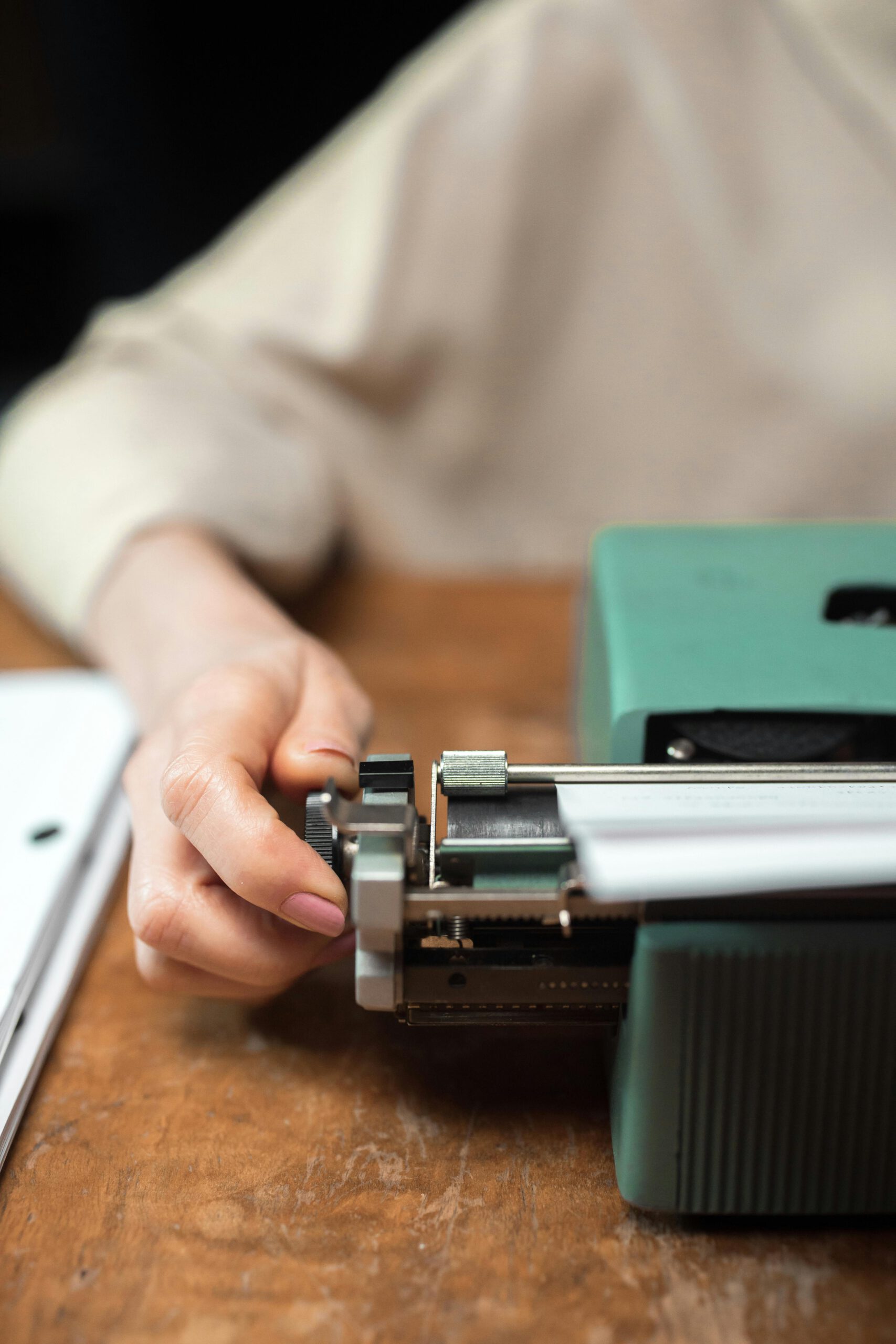 A person using a vintage typewriter in an office setting, focusing on the hand and typewriter details.